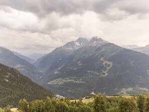 A mountainous landscape with a valley, a winding road, and a small settlement. - Spacious ski-in apartment with balcony and covered parking (La Rosière)