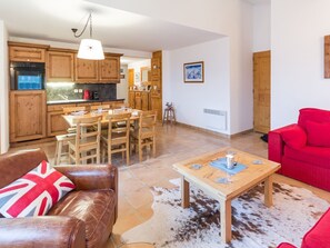 A cozy living room with a leather sofa, a red couch, and a wooden coffee table. - Spacious ski-in apartment with balcony and covered parking (La Rosière)