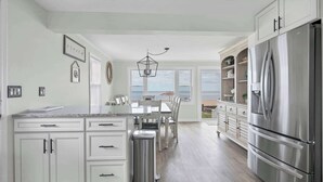 A kitchen with a large island, stainless steel appliances, and a view to the outside. - Duckling Crossing | Beach House on the Sand (Westbrook)