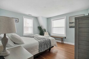 Une chambre à coucher avec un lit, des tables de chevet, une lampe et une fenêtre avec des stores.