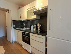 A modern kitchen with a stainless steel sink, a coffee machine, and a built-in oven.