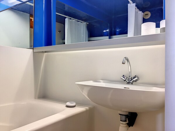 Un baño con un lavamanos blanco, una bañera y un espejo sobre el lavamanos.