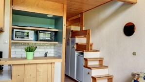 A compact kitchen with wooden cabinetry, a microwave, a toaster, and a refrigerator.