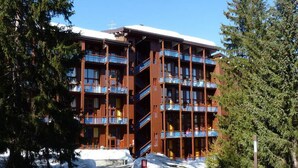A multi-story hotel with balconies, surrounded by snow and trees.