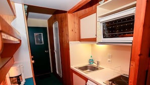 A compact kitchen with wooden cabinets, a built-in oven, a sink, and a coffee machine. - Ski-to-door studio with sunny balcony (Les Arcs 1800)