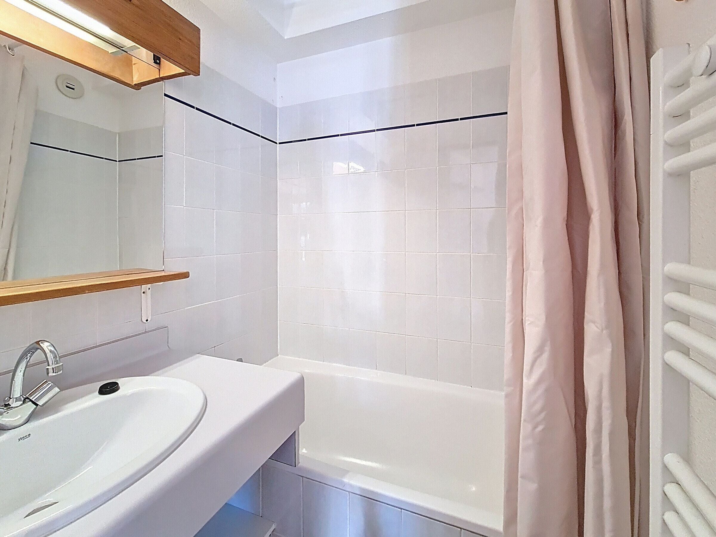 A bathroom with a white sink, mirror, and bathtub.