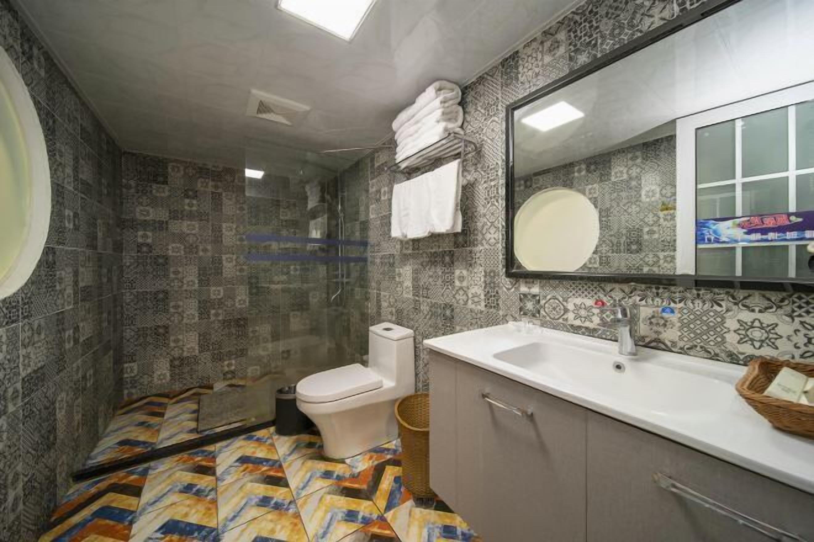 A bathroom with patterned tiles, a toilet, a sink, and a mirror.