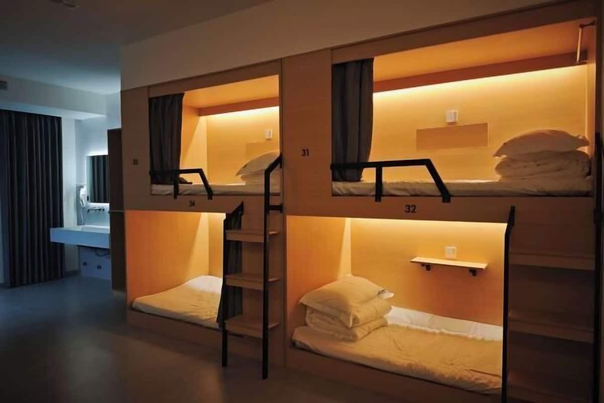 A dormitory-style room with bunk beds, each bed numbered, and a small shelf above the lower bunk.