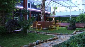 An outdoor seating area with a stone pathway, wooden deck, and yellow chairs.