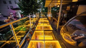 A glass bridge with illuminated panels, surrounded by potted plants and a car parked nearby. - Mugen Town Residence (Zixing)