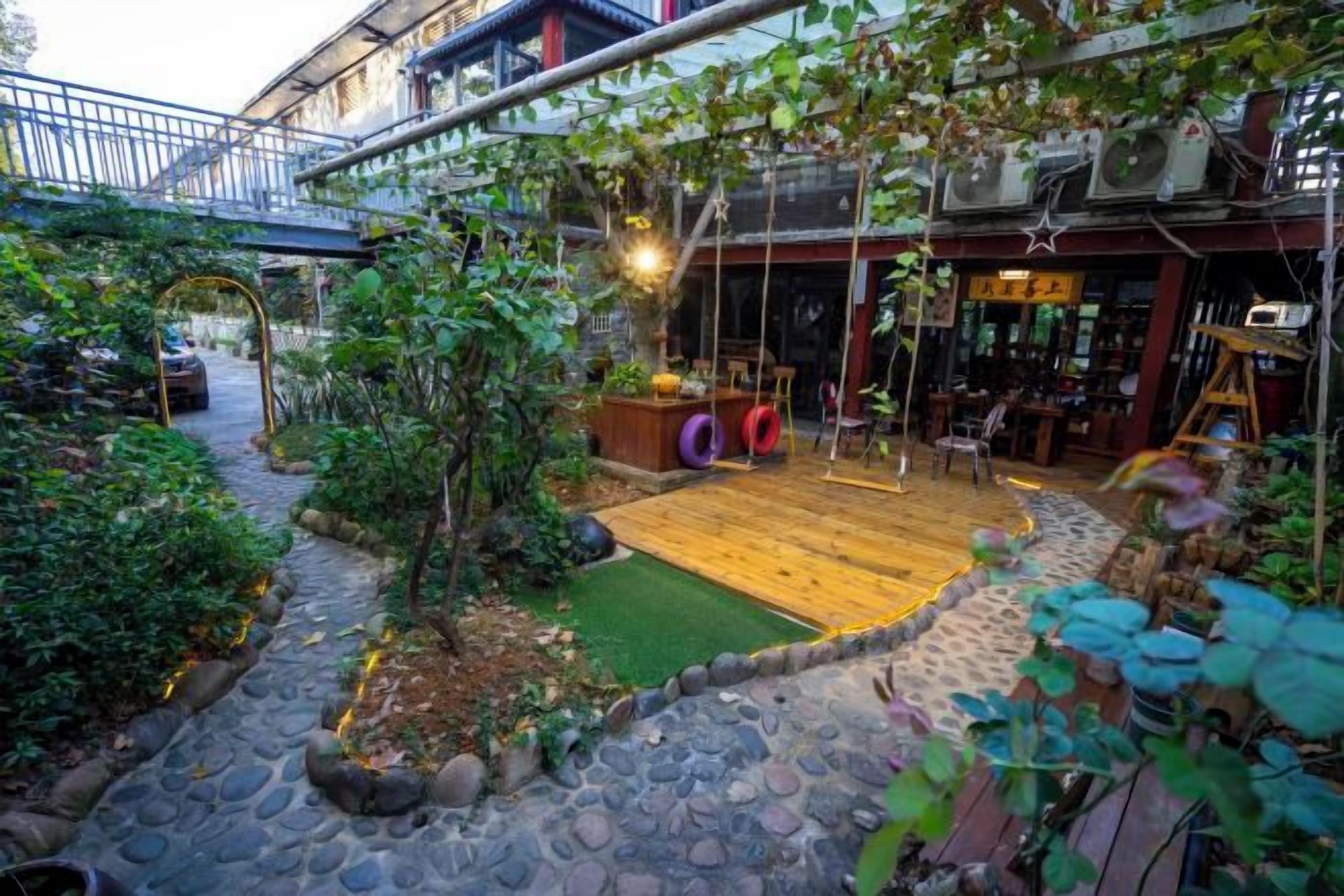 A courtyard with a wooden deck, stone pathway, and greenery.