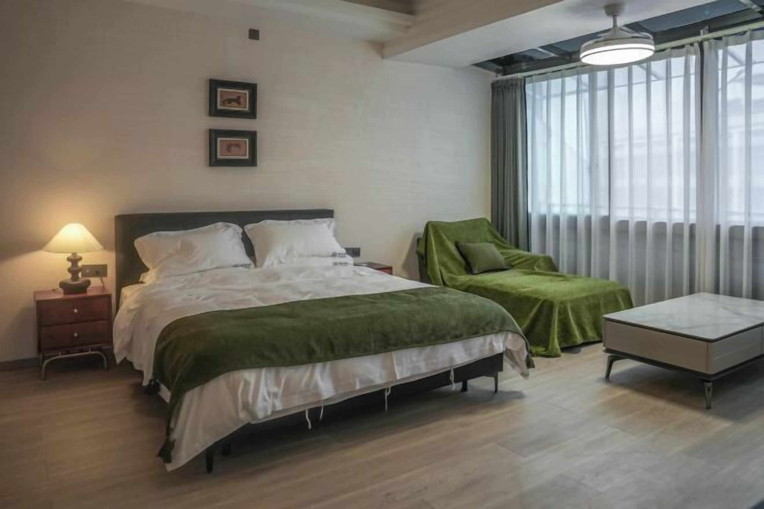 Un dormitorio con cama, mesita de noche, lámpara y ventana con cortinas.