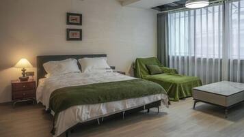 Un dormitorio con cama, mesita de noche, lámpara y ventana con cortinas.