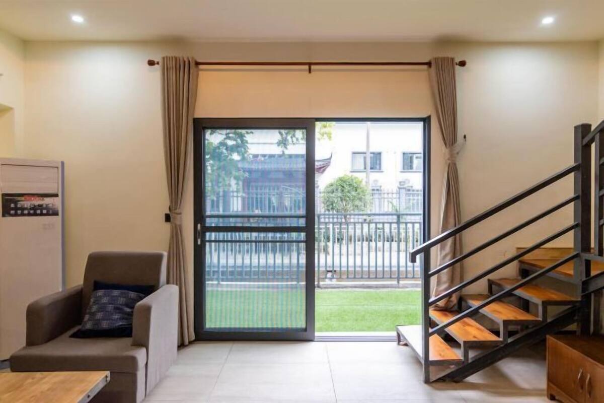 A modern living room with a sofa, a coffee table, and a staircase leading to an outdoor balcony.