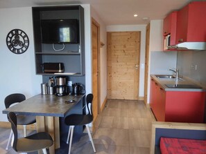 A compact kitchen with a dining area, wooden door, and modern appliances.