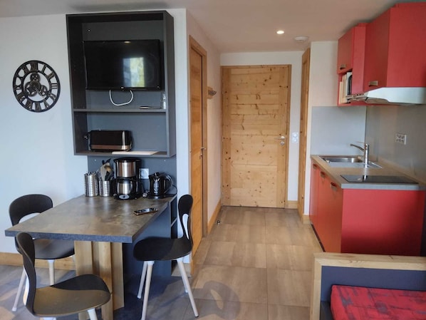 A compact kitchen with a dining area, wooden door, and modern appliances.