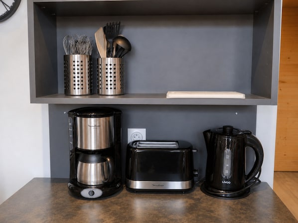 Una encimera de cocina con cafetera, tostadora y hervidor.
