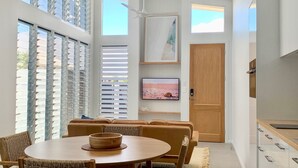 Uma sala de estar moderna com uma mesa redonda de madeira, um sofá e uma televisão na parede.