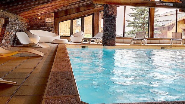 Une piscine intérieure dotée de sièges modernes et de grandes fenêtres.