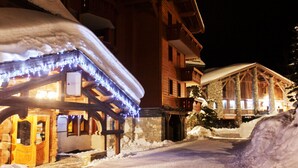 Un bâtiment recouvert de neige, doté d’une façade en bois et d’une entrée en pierre.