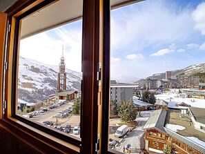A hotel with a view of a snowy mountain and a church. - Cozy studio for 2, pets allowed, ski-in ski-out (Les Menuires)