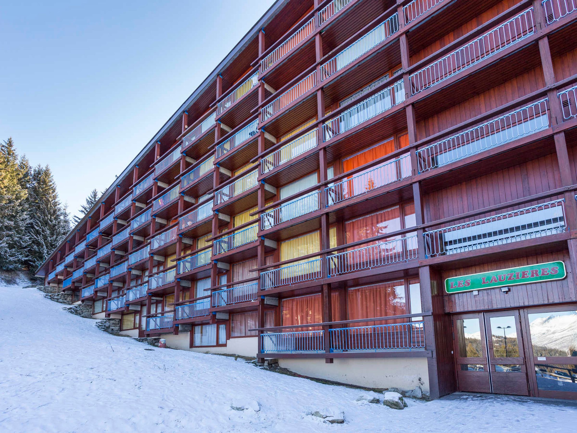 Et hotel med flere etager, altaner og et sneklædt landskab. Skiltet viser "LES LAUZIÈRES".