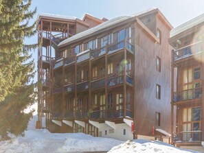 A multi-story wooden building with balconies and a ski lift visible.