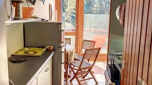 A compact kitchen with a dining area, a stove, and a view of the outdoors.