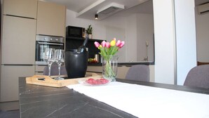 A modern kitchen with a marble countertop, a wooden cutting board, a glass vase with tulips, and a bowl of raspberries. - Apartment in Rovinjsko Selo for 6 persons (Rovinjsko Selo)