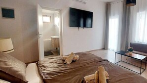 A hotel room with a large bed, a TV mounted on the wall, a small table with a plant, and a window with curtains. - Apartment in Rovinjsko Selo for 6 persons (Rovinjsko Selo)