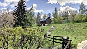 A rustic cabin on a grassy hill with a wooden staircase leading up to it. - Spacious and comfortable chalet with pool table, near lifts (Le Corbier)