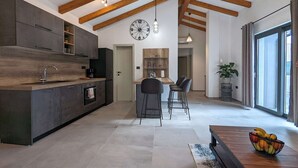 Una cocina moderna con armarios oscuros, techo de madera y una isla central con taburetes de bar.