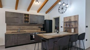 Una cocina moderna con una isla central, taburetes de bar, horno empotrado y un refrigerador negro.