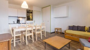 A compact living space with a kitchenette, a dining area, a sofa, and a small table.