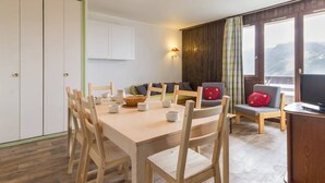 A dining area with a table set for six, wooden chairs, a buffet table, and a sofa with cushions.