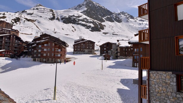 A snow-covered ski resort with multiple chalet-style buildings, a mountain in the background, and a clear sky. - Cozy studio at the slopes - Pets allowed (Belle Plagne)