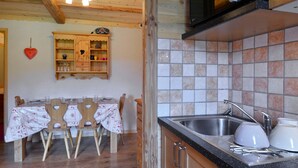 A kitchen with wooden cabinets, a tiled backsplash, and a dining area with a table and chairs. - Cozy studio at the slopes - Pets allowed (Belle Plagne)