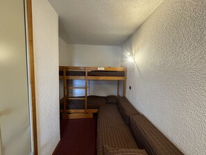 Una habitación pequeña con literas y un banco.