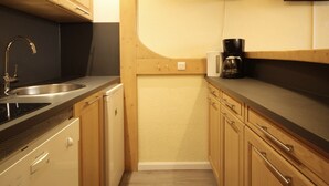 A compact kitchen with wooden cabinets, a stainless steel sink, and a coffee maker.