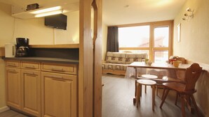 A kitchen with wooden cabinets, a coffee maker, and a television on the wall.