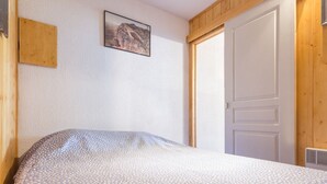 A bedroom with a bed, a wooden door, and a framed picture on the wall.