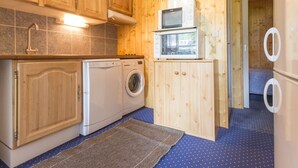 A compact kitchen with wooden cabinets, a washing machine, and a microwave.