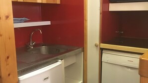 Uma cozinha compacta com pia, lava-louças Bosch e uma pequena geladeira.