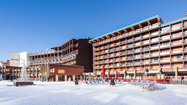 Um hotel com vários andares, área de estar ao ar livre e terreno coberto de neve.