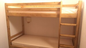 Uma cama beliche com escada, colchão e luminária fixada na parede.