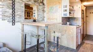 Una cucina moderna con parete a parete in pietra, mobili in legno e un'area bar con sgabelli.