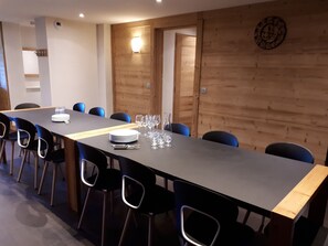 A conference room with a long table, chairs, and a clock on the wall.