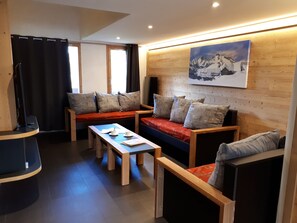 A modern living room with a sofa, two armchairs, a coffee table, and a television.
