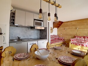 Eine kompakte Küche mit Mikrowelle, Herd und einem Essplatz mit Holztisch, gedeckt für eine Mahlzeit.