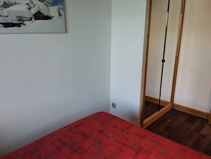 A room with a red carpeted bed, a white wall, and a painting of a snowy landscape. - Beautiful renovated apartment 7 pers · Easy access · Pets allowed (La Plagne Montchavin Les Coches)